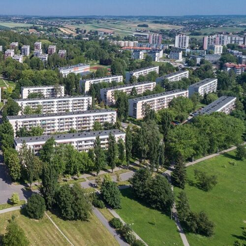 Widok z lotu ptaka na osiedle czterech pór roku. Trzy rzędy bloków obok siebie, stojących wobec siebie pod delikatnych kątem. Dookoła dużo drzew. Spacer. Szczegółowe informacje we wpisie.