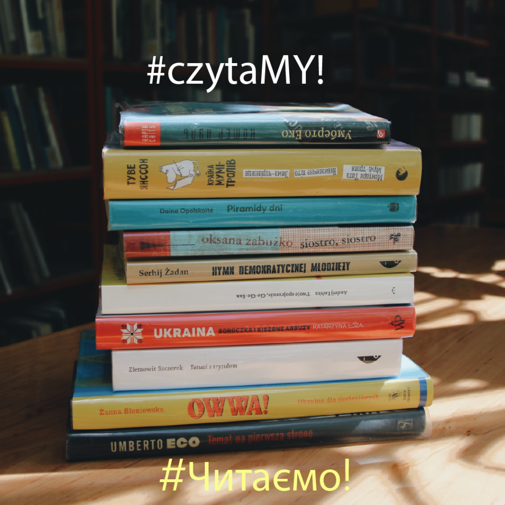 Stosik książek ustawiony na stoliku. Pada na nie ciepłe światło z okna. W tle regały biblioteczne. Napis hasztag czytamy po polsku i ukraińsku.